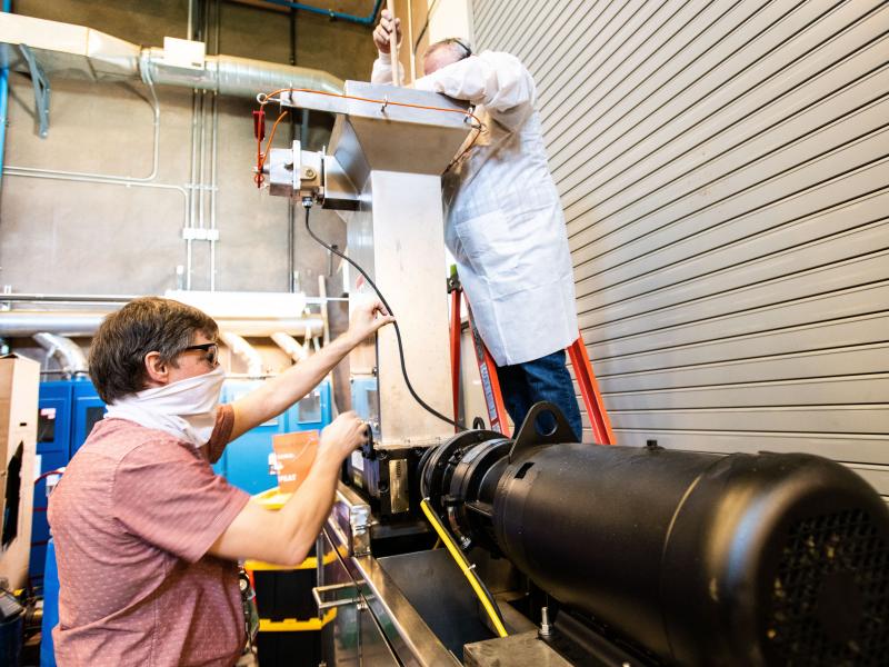 Picture of two people operating a customized industrial grinder at Pacific Northwest National Laboratory 