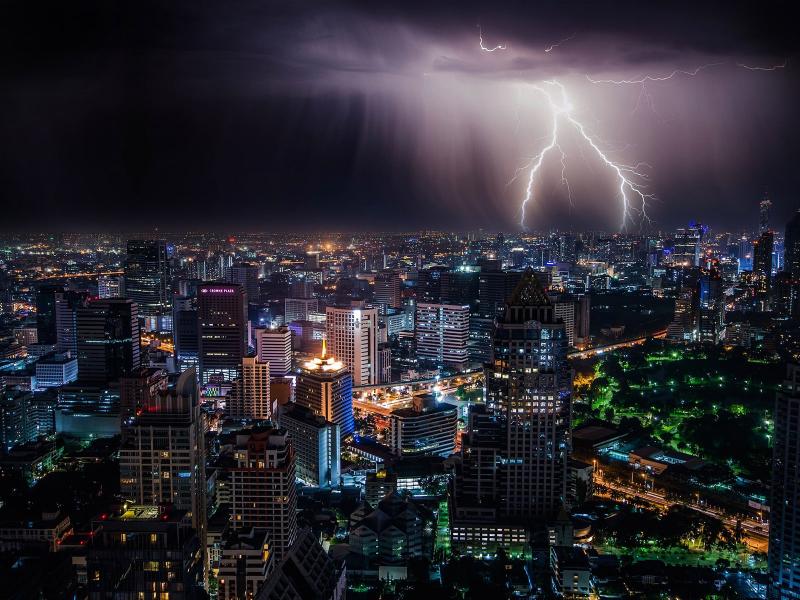 A thunderstorm stirs above a cityscape, as lightning touches down near buildings. The presence of urban land can amplify hazardous weather, according to new research from PNNL scientists. (Photo by Free-Photos | Pixabay.com)