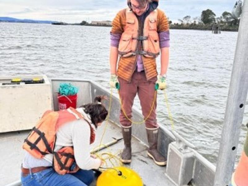 two researchers on a boat retrieving a Acoustic Doppler Current Profiler from the water
