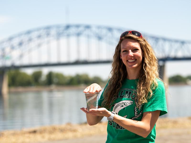 woman in green shirt holding a cup with fish in it