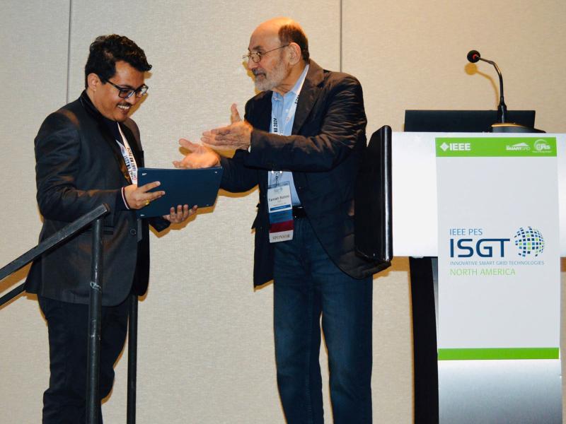 Samrat Acharya accepts an award from a presenter