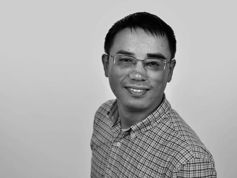 Black and white photograph of a smiling man with glasses