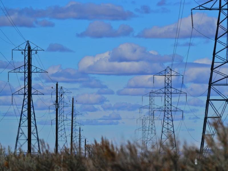 Power lines and poles in the foreground of a cloudy blue sky