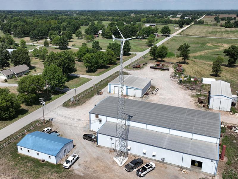 Aerial view of a wind turbine near a large building in a rural setting