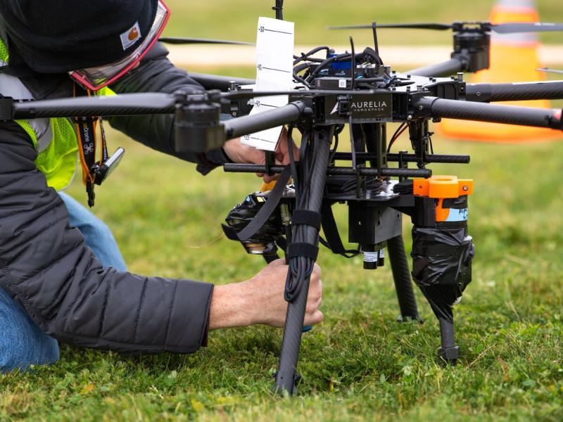Person fixing sensors on drone in grass field