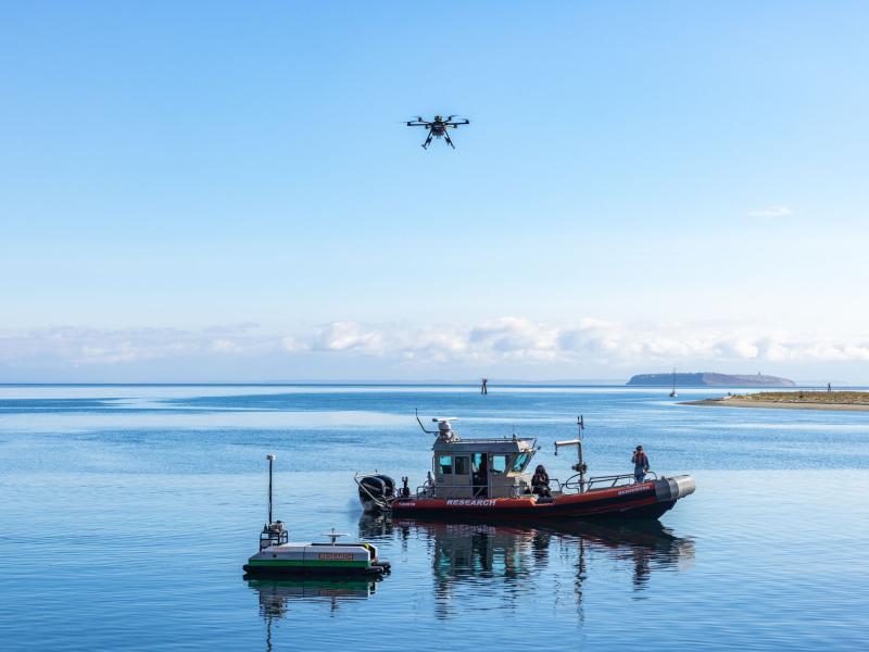 A research boat, drone, and unmanned surface vehicle on water