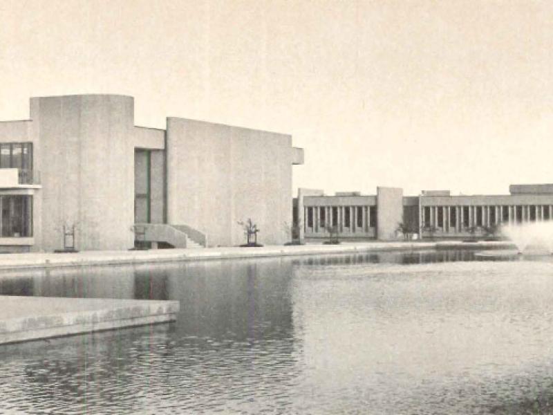 a sepia-toned photo of a large reflecting pool surrounded by brutalist, concrete buildings