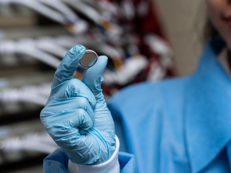 Photograph of someone holding up a coin-size battery