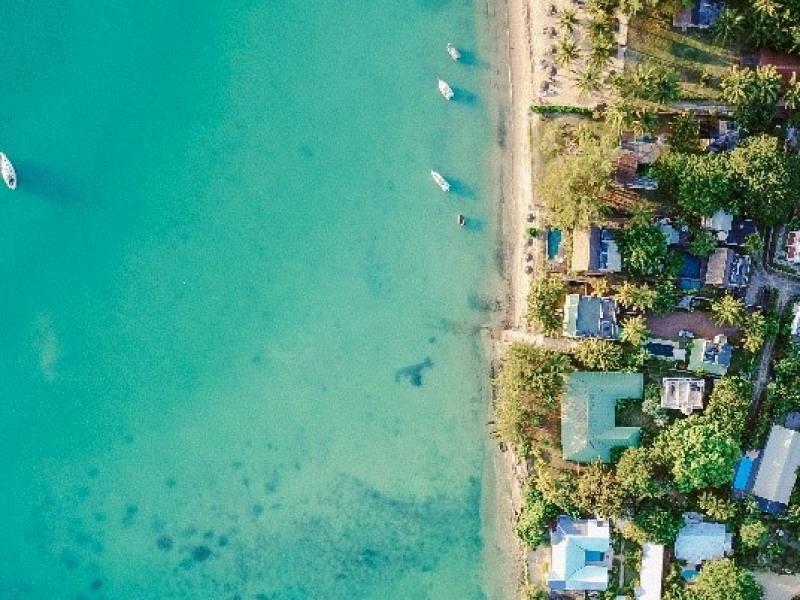 an aerial view of beach houses on the coast with blue water