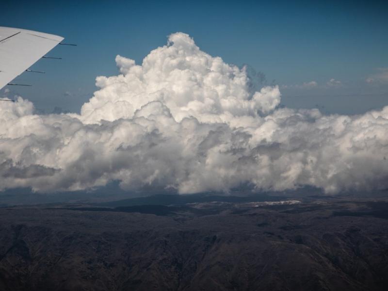 image taken from a plane of a large cloud system over mountains