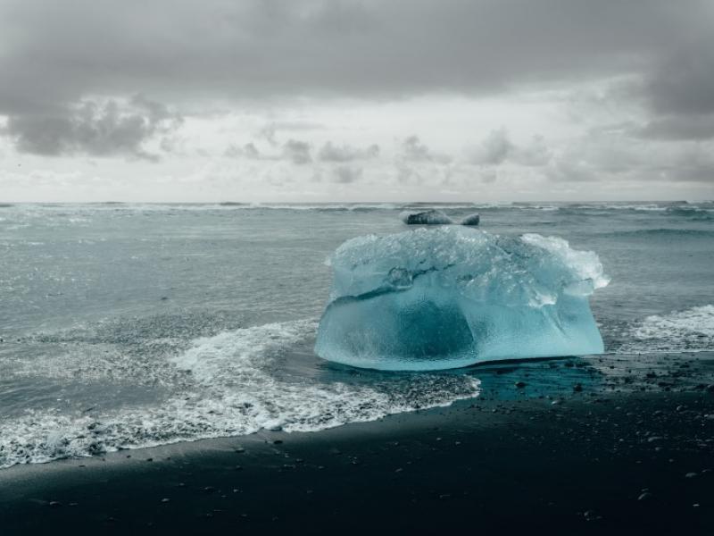 a blue-green iceberg on the beach