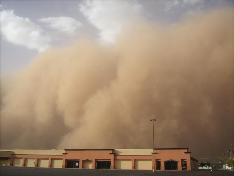 A wave of sand about to blow over a building