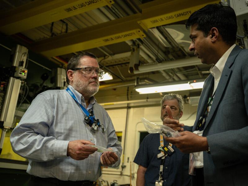 Dr. Michael Goff, principal deputy assistant secretary for DOE’s Office of Nuclear Energy, holds material and listens to someone speaking to him in laboratory setting