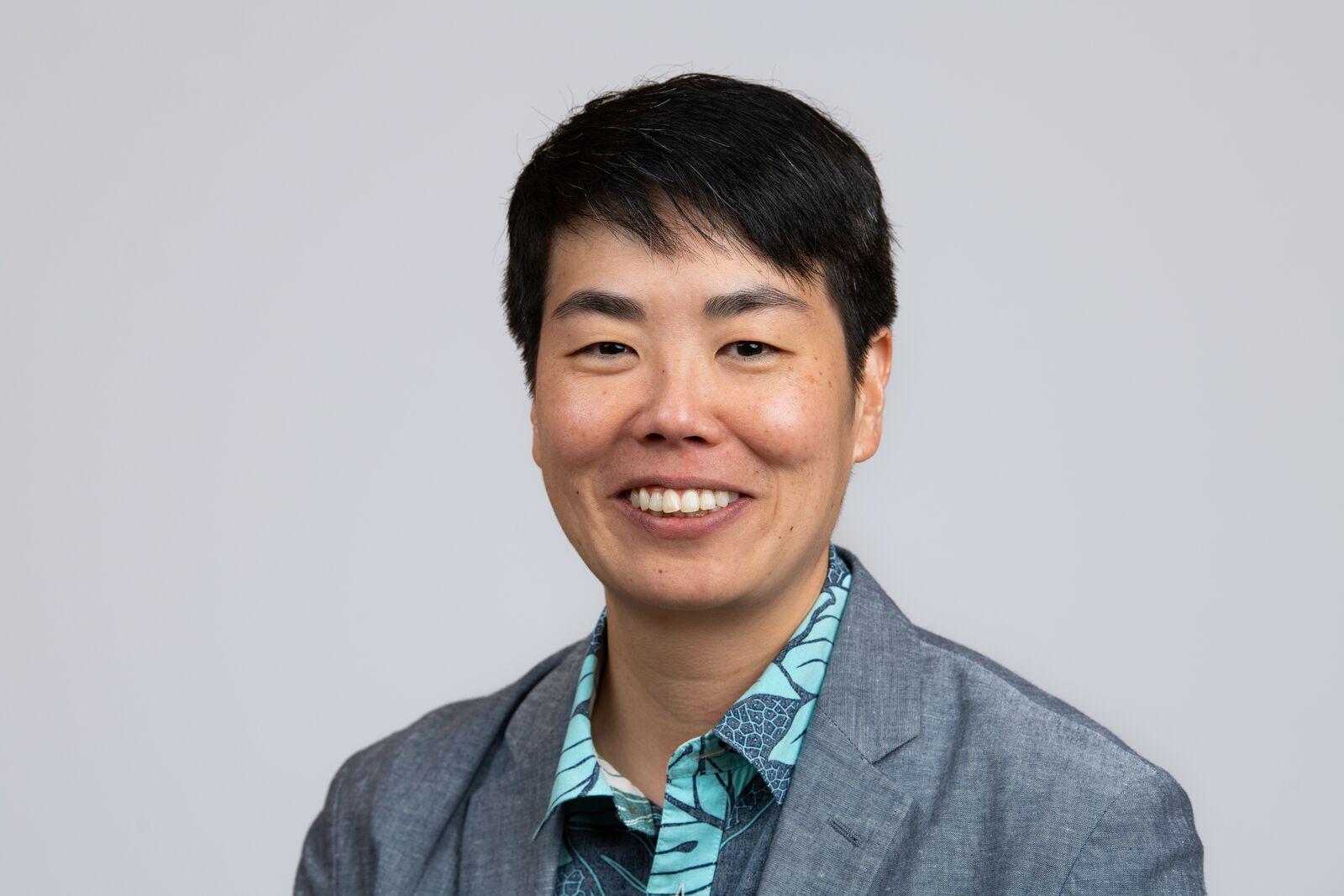Photo of dark haired person wearing shirt and suit jacket