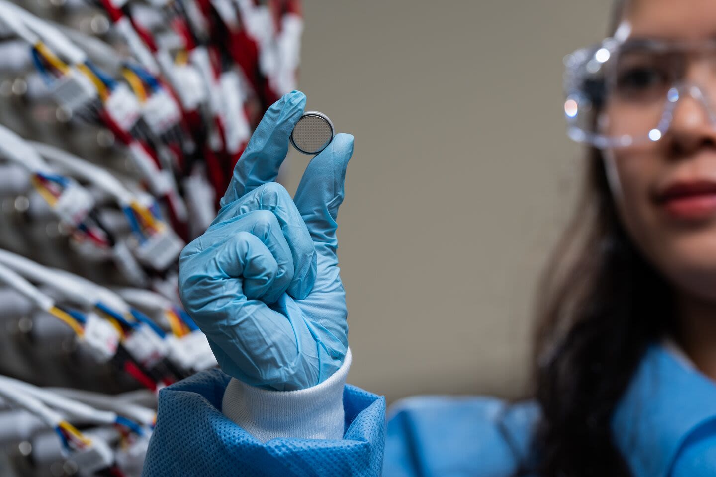 A gloved hand holding a circular coin battery
