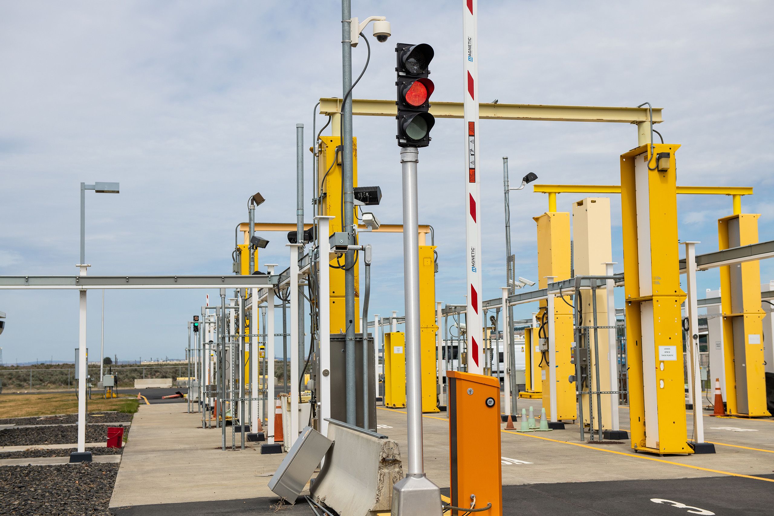 an outdoor radiation monitoring station with large, yellow metal gates, striped barriers and traffic signals