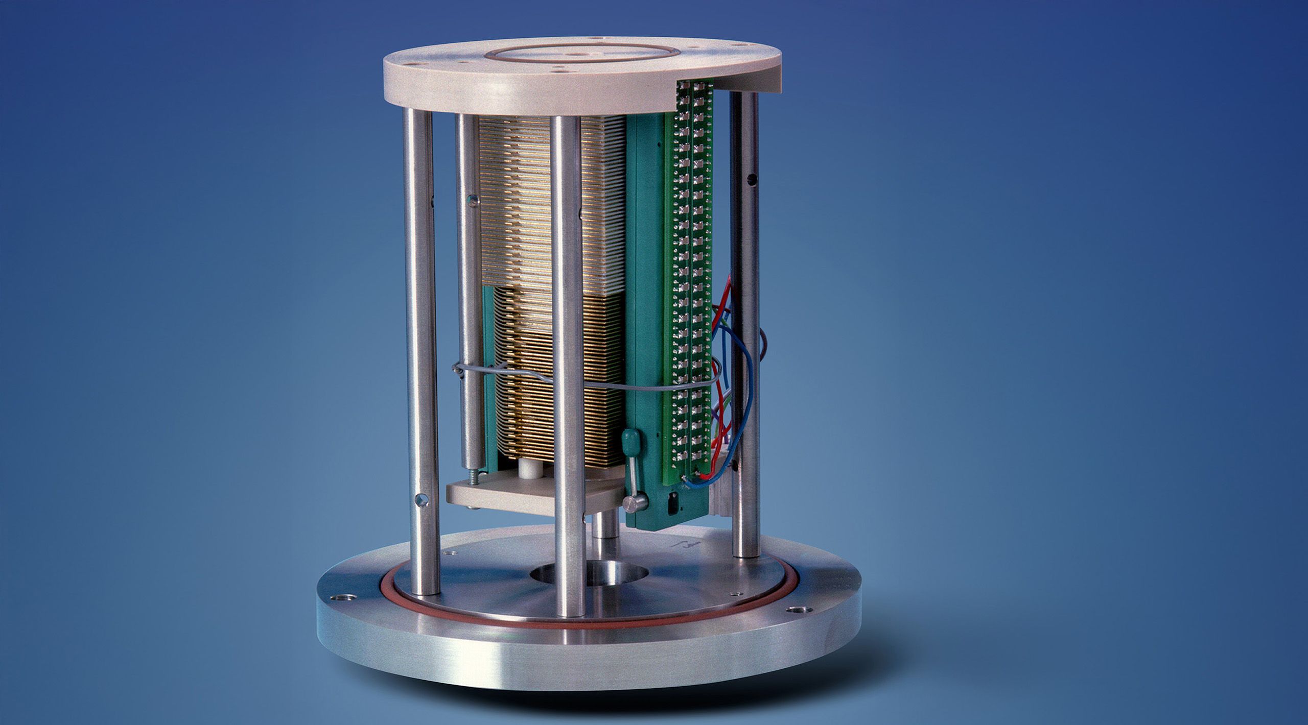 The electrodynamic ion funnel is a cylindrical device with open sides. It is pictured on a blue background.