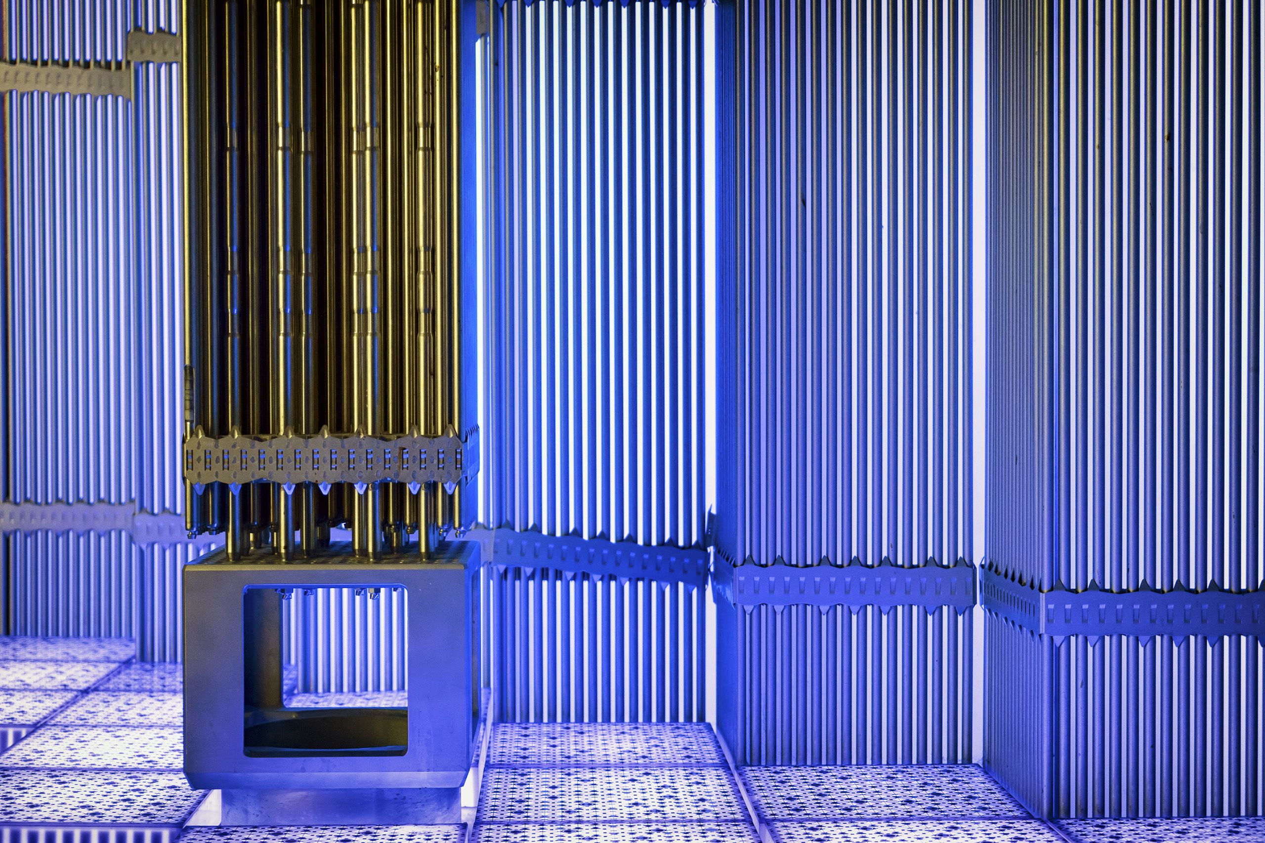 inside view of warm-hued metallic rods inside a cool-hued reactor